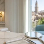 Marcador quirúrgico, pinzas de precisión y espejo de mano sobre mostrador de mármol en una clínica luminosa de Córdoba, simbolizando la valoración y el diseño de un injerto de barba y cejas